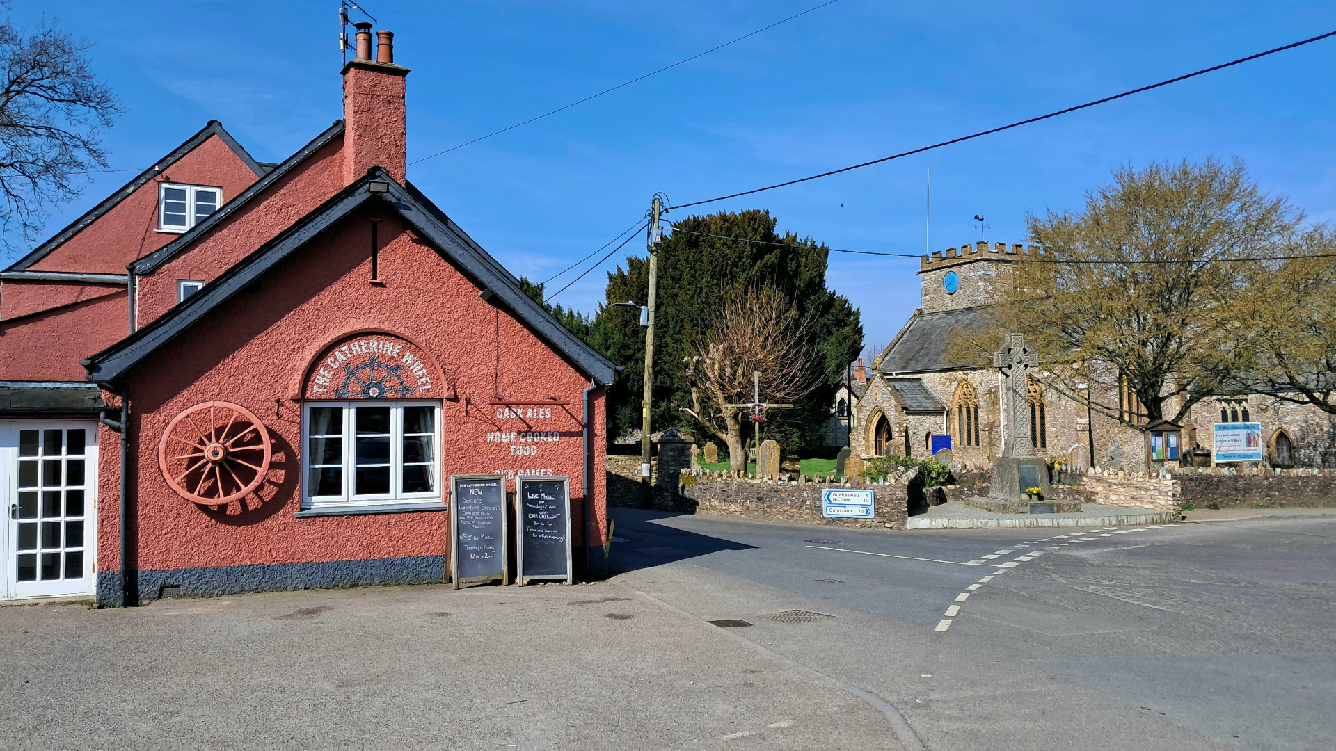 Red-painted two-storey pub building with a painted wagon wheel on the facade
