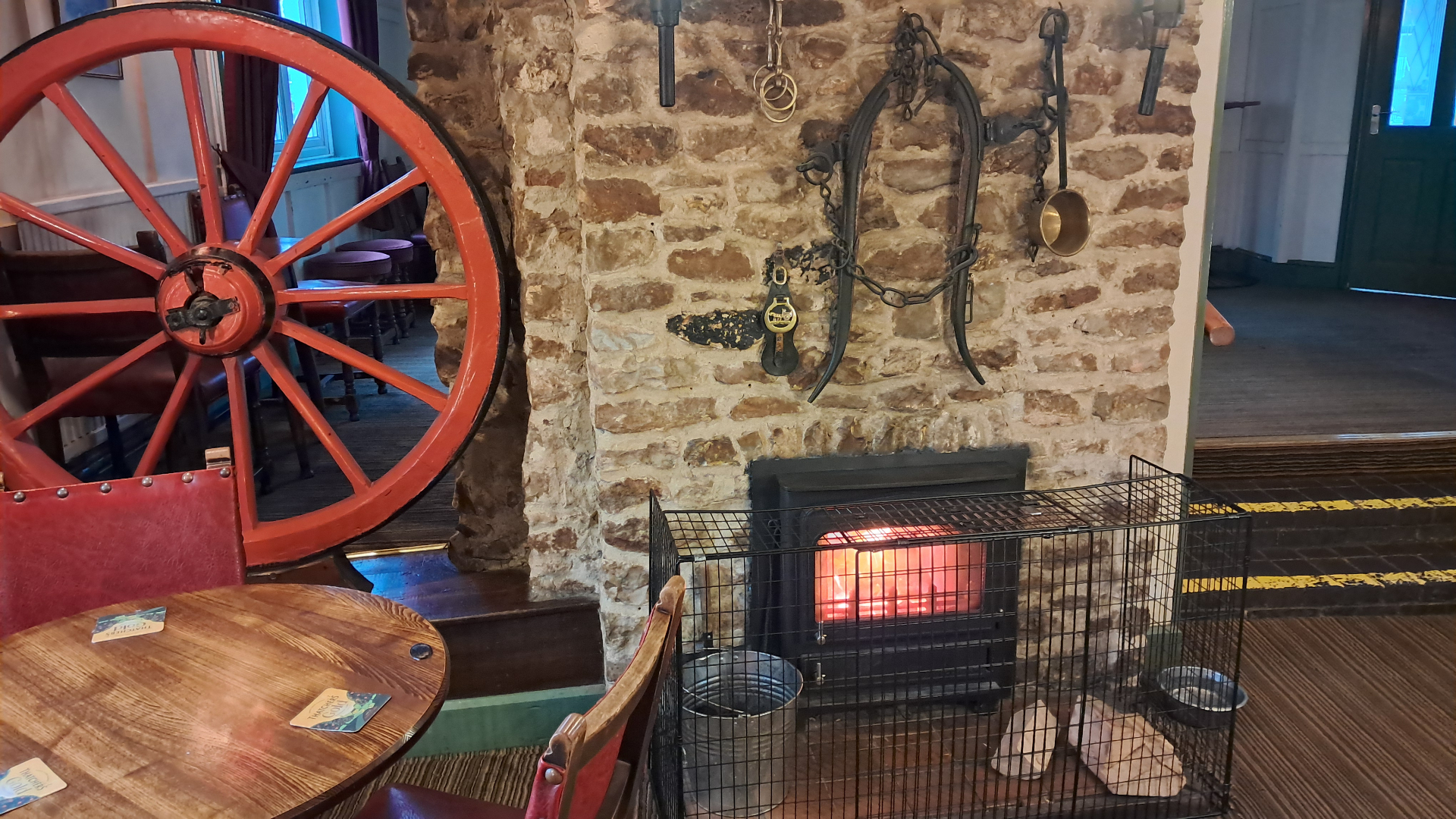 Cosy pub corner with stone fireplace, wagon wheel and warm fire
